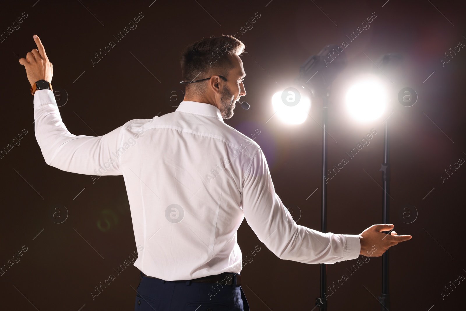 Photo of Motivational speaker with headset performing on stage, back view
