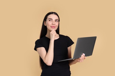 Photo of Thoughtful woman with laptop on beige background
