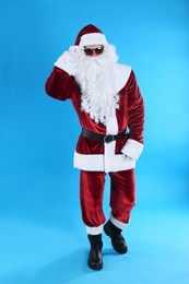 Full length portrait of Santa Claus with sunglasses on light blue background
