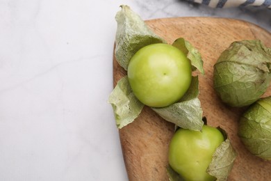 Fresh green tomatillos with husk on light table, top view. Space for text