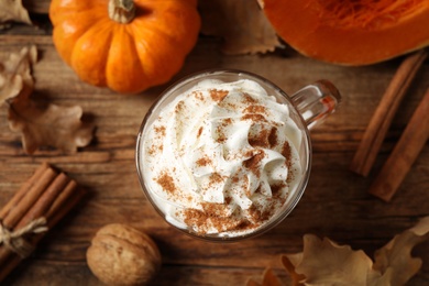 Photo of Delicious pumpkin latte on wooden table, top view