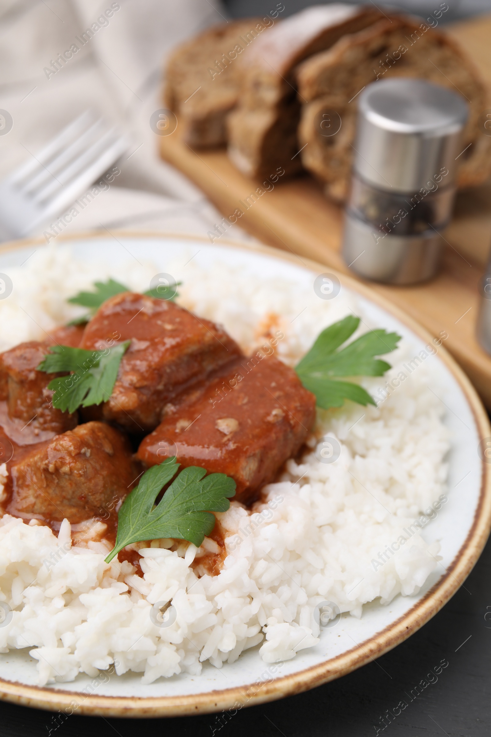 Photo of Delicious goulash served with rice on table, closeup