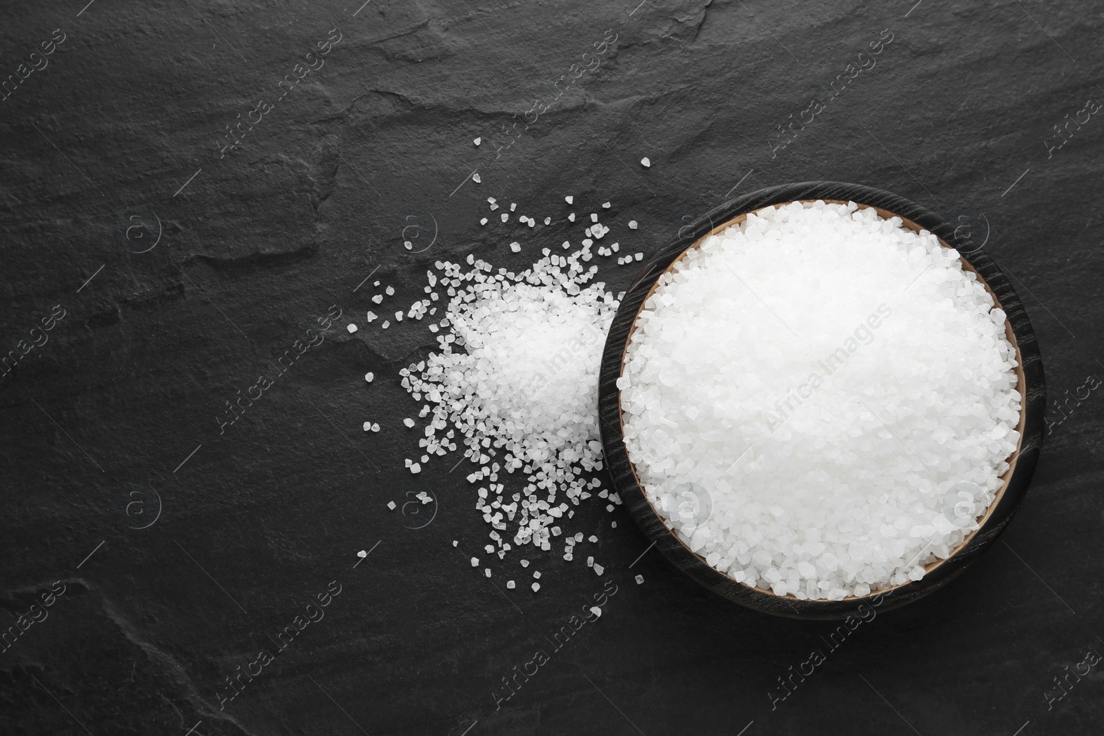 Photo of Natural sea salt on black table, flat lay, Space for text