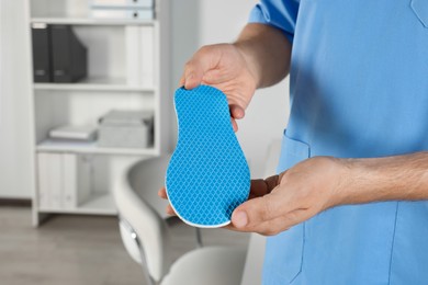 Male orthopedist showing insole in hospital, closeup