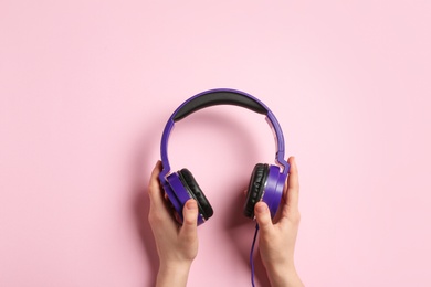 Photo of Woman holding stylish headphones on color background, closeup