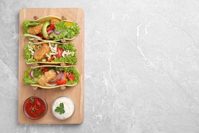 Photo of Delicious fish tacos served on grey marble table, top view. Space for text