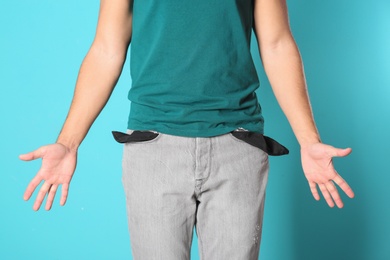 Man showing empty pockets on color background, closeup