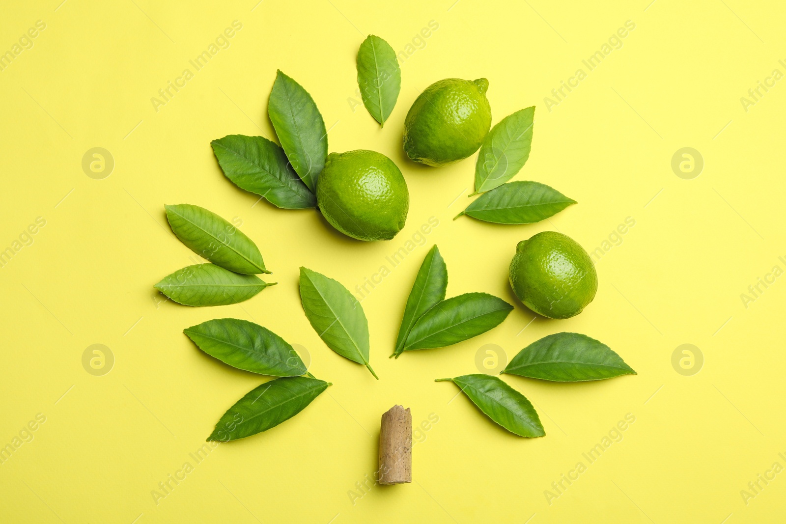 Photo of Flat lay composition with fresh green citrus leaves and limes on yellow background