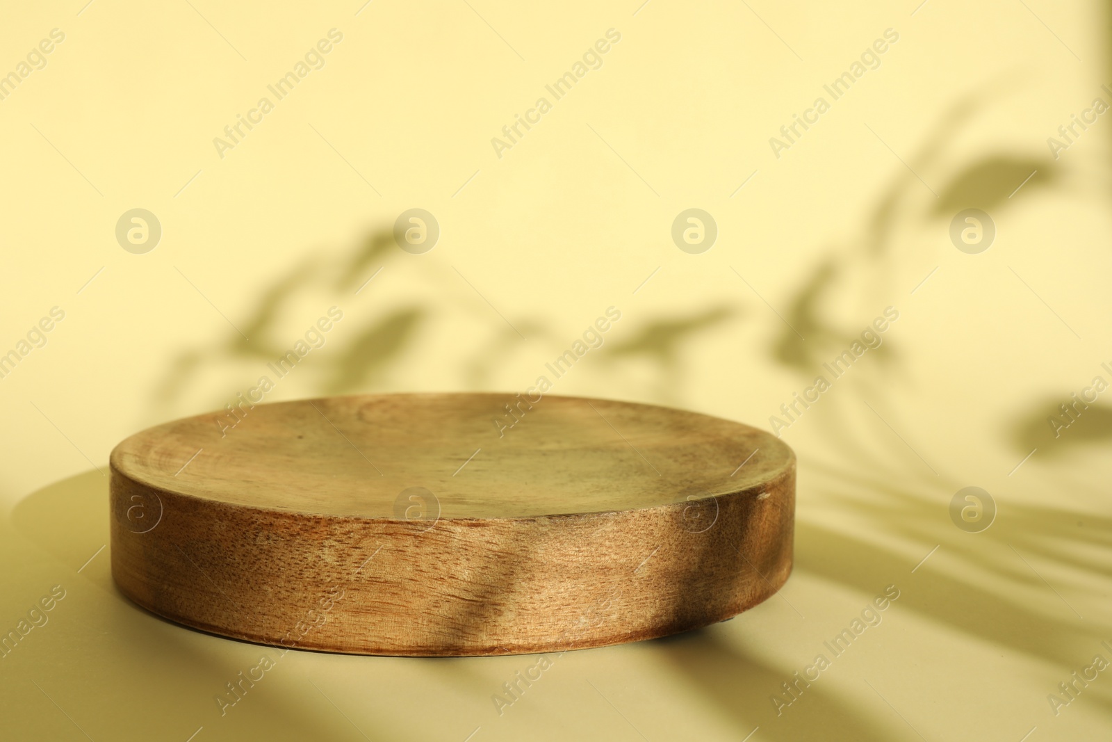 Photo of Presentation of product. Wooden podium on yellow background. Space for text