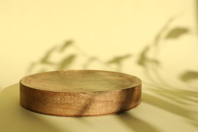 Photo of Presentation of product. Wooden podium on yellow background. Space for text