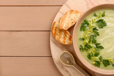 Delicious leek soup served on beige wooden table, top view. Space for text