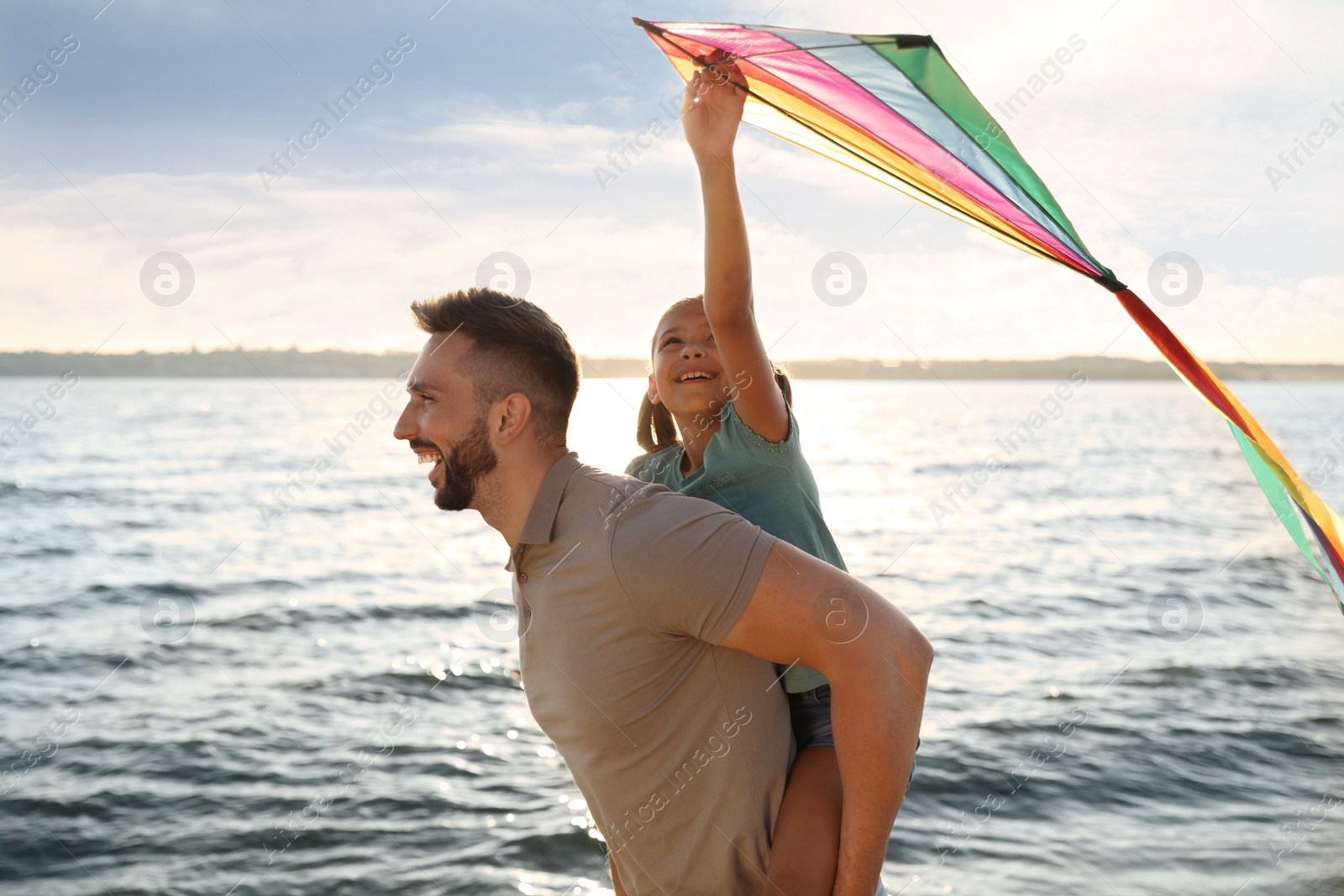 Photo of Happy father and his child playing with kite near sea. Spending time in nature