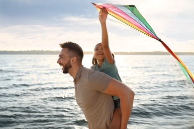 Photo of Happy father and his child playing with kite near sea. Spending time in nature