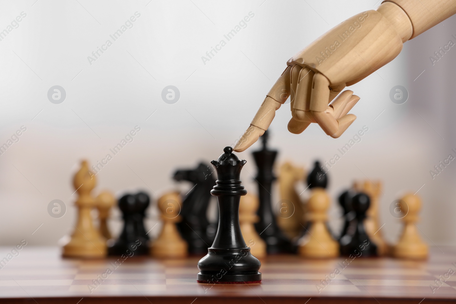 Photo of Robot moving chess piece on board against light background, closeup. Wooden hand representing artificial intelligence