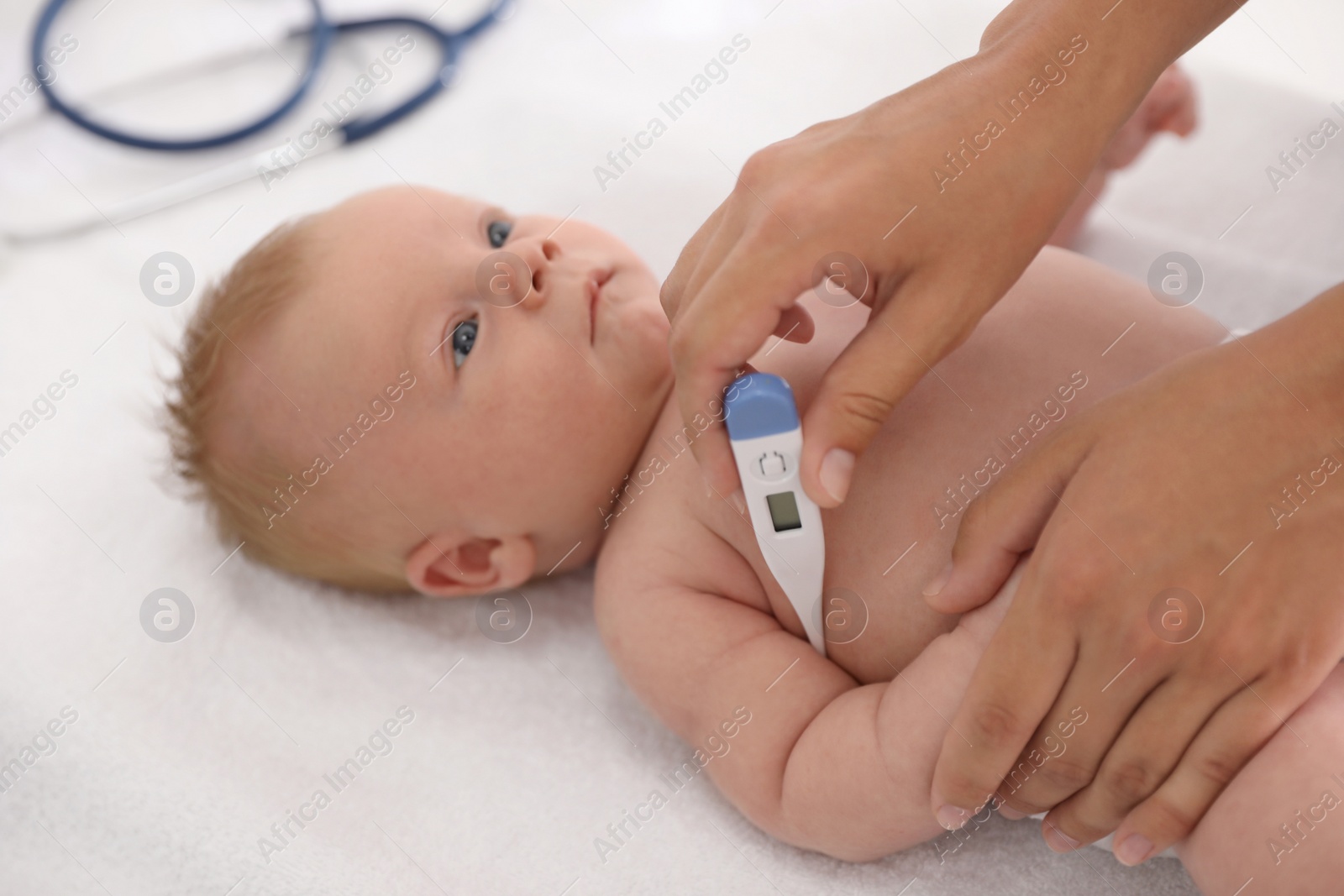 Photo of Doctor measuring temperature of little baby with digital thermometer indoors, closeup. Health care