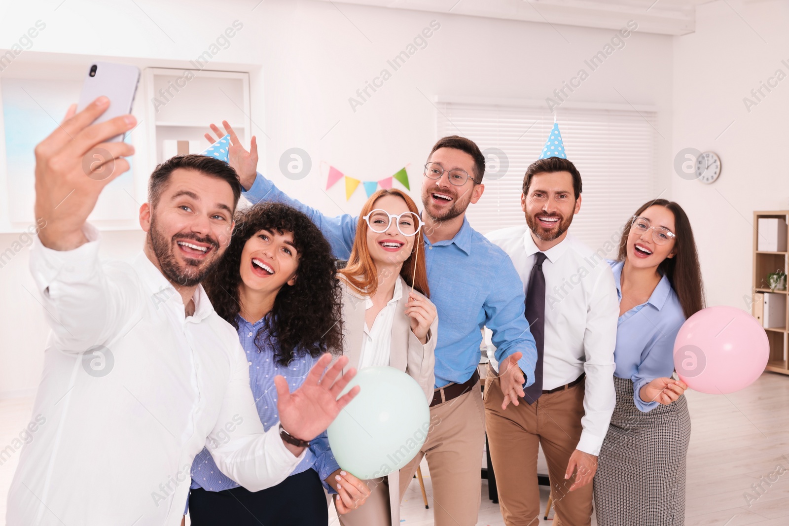 Photo of Coworkers taking selfie during office party indoors