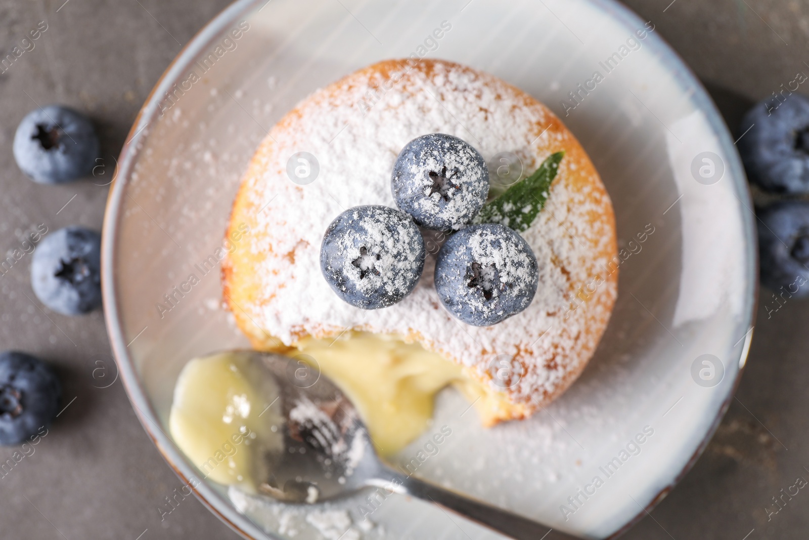 Photo of Tasty vanilla fondant with white chocolate and blueberries on grey table, flat lay