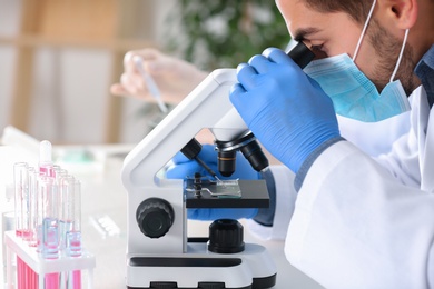 Photo of Male scientist working with microscope in laboratory. Research and analysis