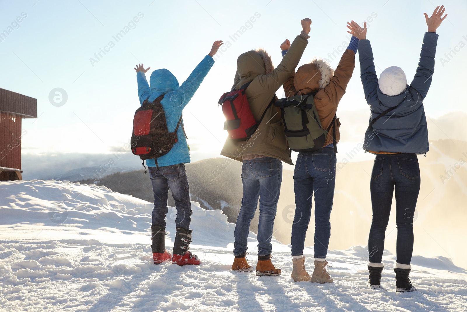 Photo of Group of excited friends with backpacks enjoying mountain view during winter vacation