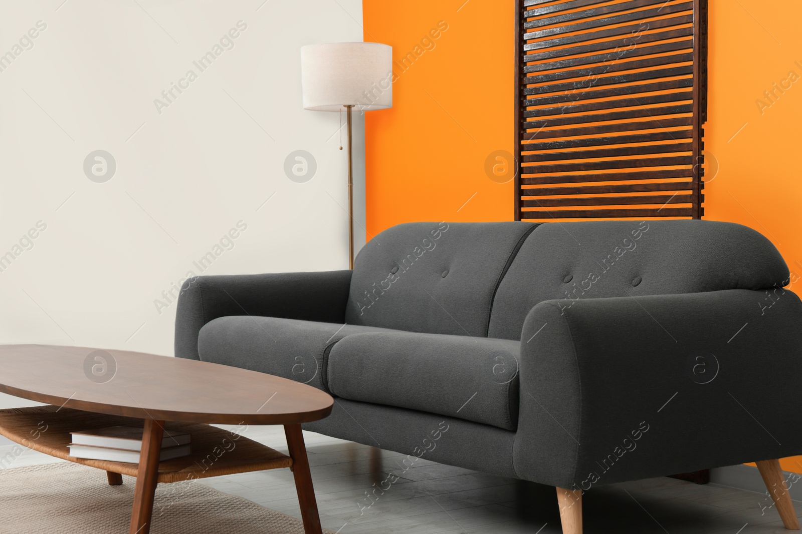 Photo of Stylish room with cosy sofa near orange wall. Interior design