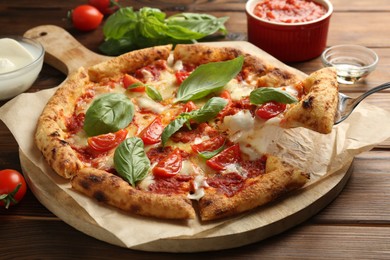 Photo of Taking piece of delicious Margherita pizza at wooden table, closeup