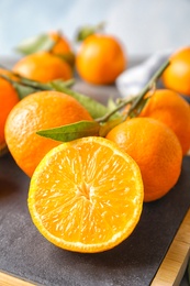 Photo of Board with ripe tangerines on table, closeup. Citrus fruit