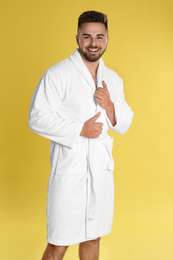 Photo of Happy young man in bathrobe on yellow background