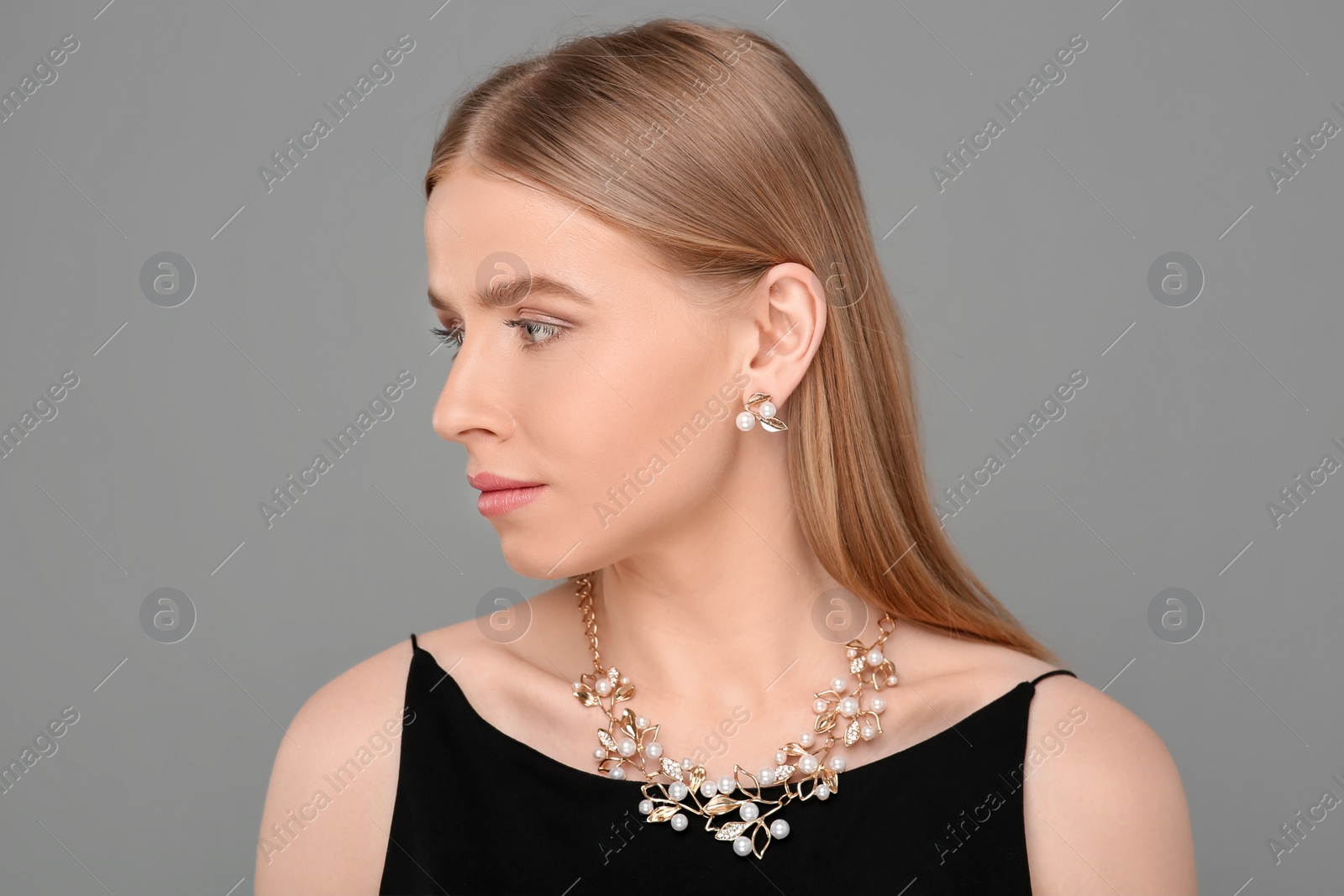 Photo of Beautiful young woman with elegant jewelry on gray background