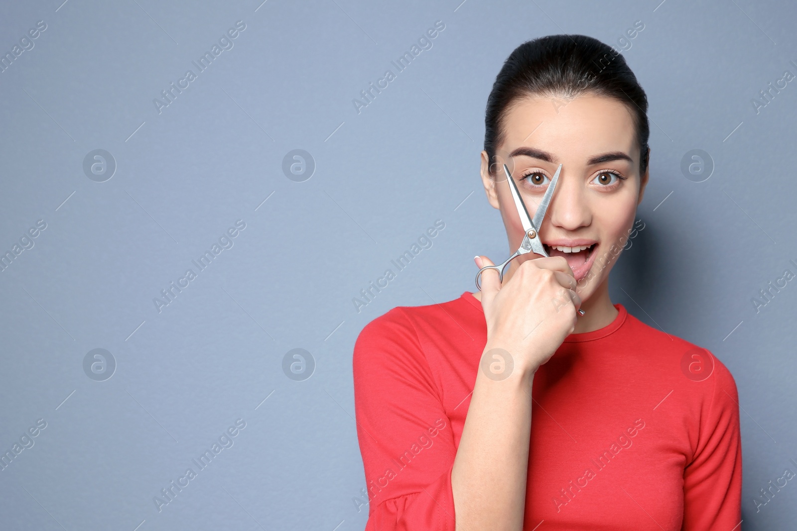 Photo of Professional hairdresser with scissors on color background