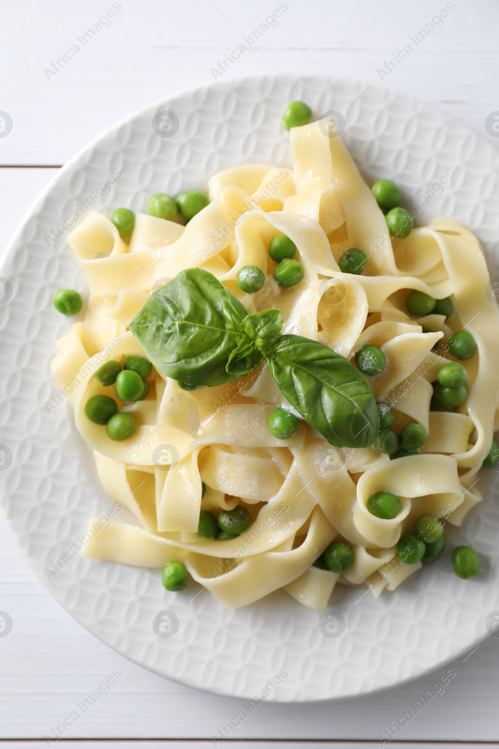 Photo of Delicious pasta with green peas on white wooden table, top view