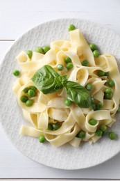 Delicious pasta with green peas on white wooden table, top view