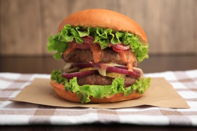 Photo of Tasty burger with vegetables, patties and lettuce on table, closeup