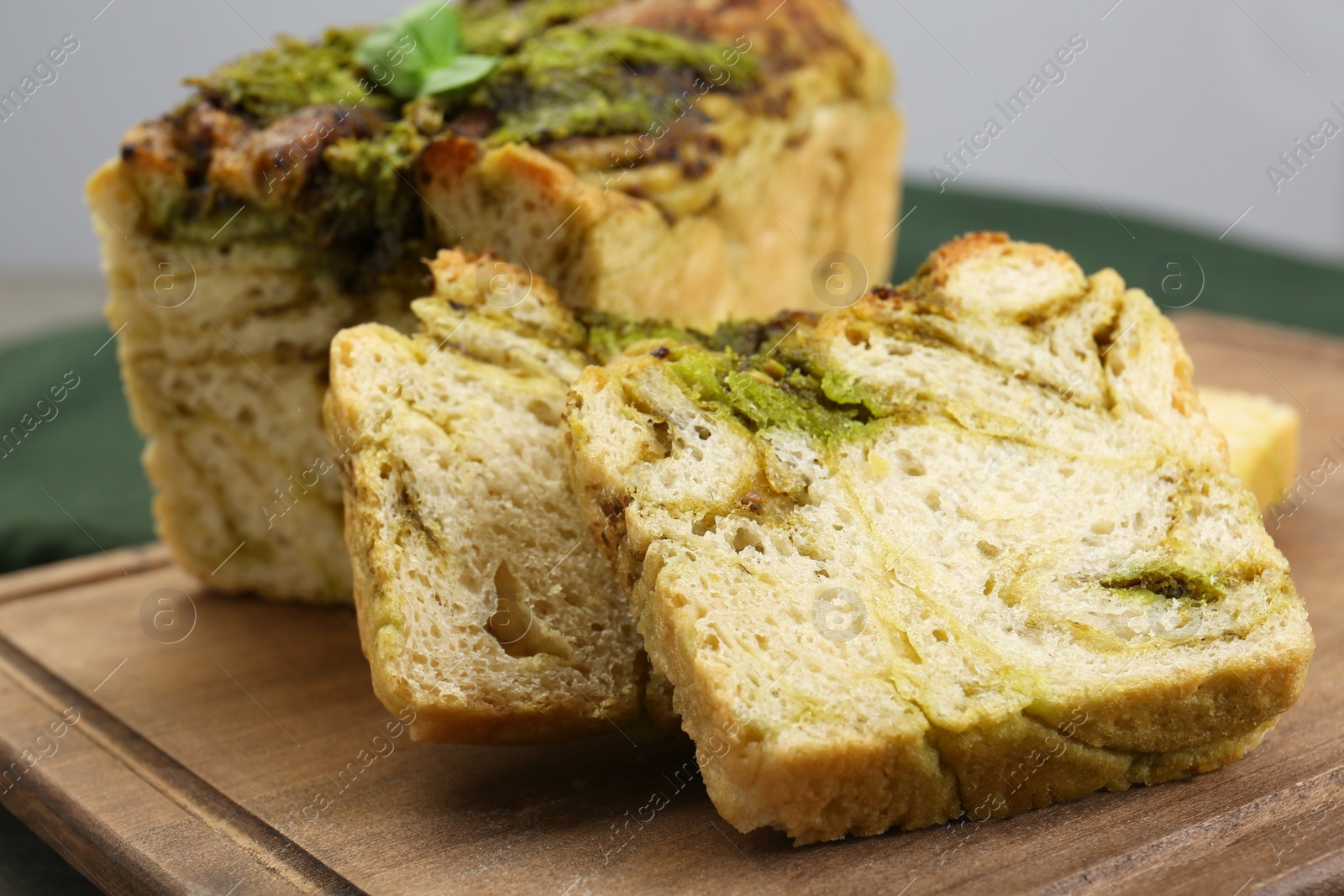 Photo of Freshly baked pesto bread on wooden board, closeup