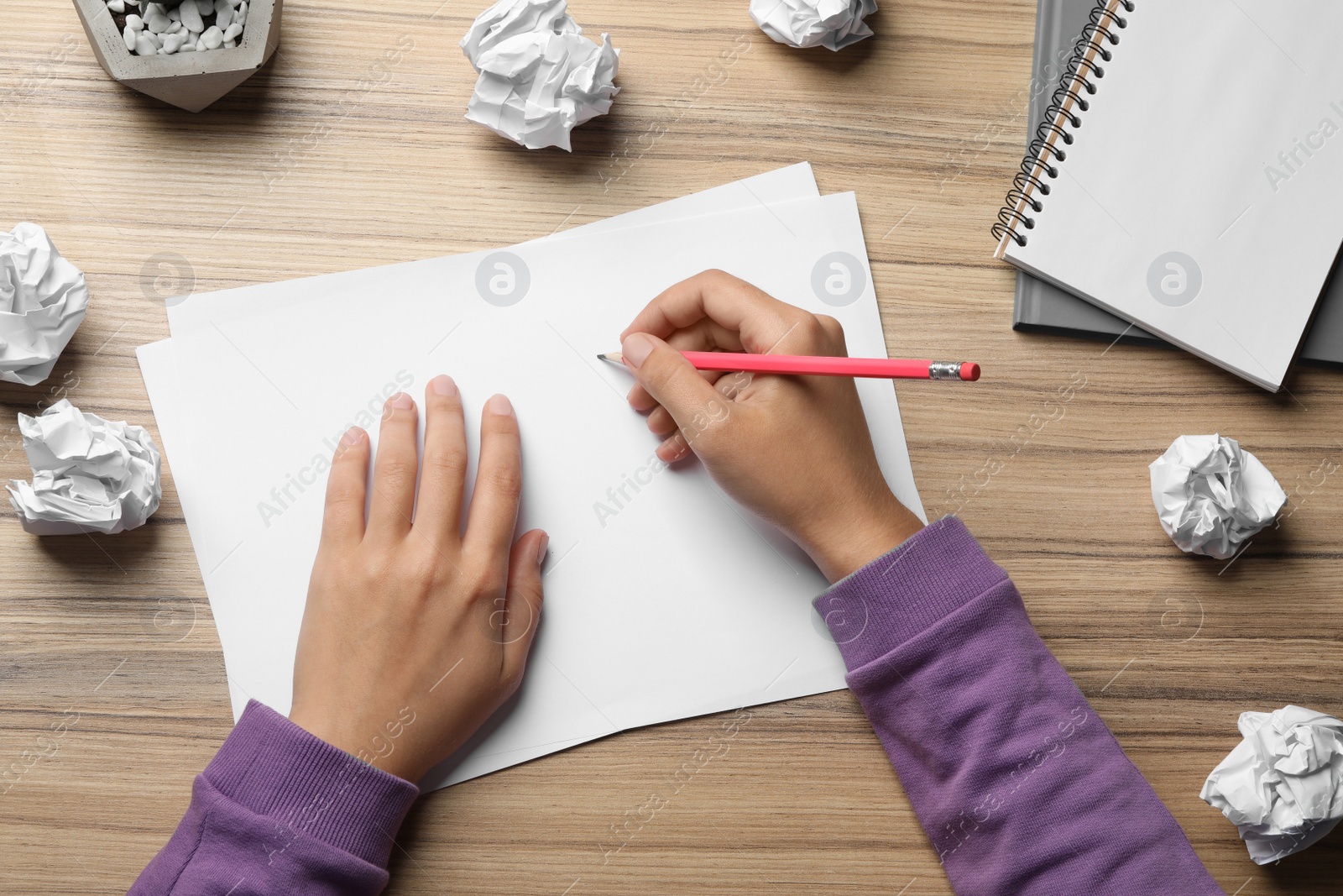 Photo of Woman working at table with crumpled paper, top view. Generating idea