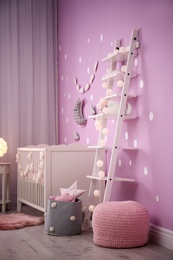 Photo of Baby room interior with crib near color wall