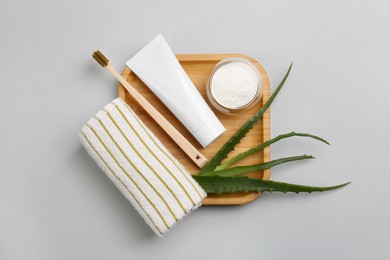 Photo of Tube of toothpaste, fresh aloe and care products on light grey background, top view