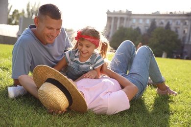 Photo of Happy parents with their child having fun on green grass. Spending time in nature