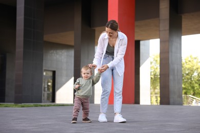 Happy nanny walking with cute little boy outdoors