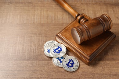 Photo of Law concept. Gavel and bitcoins on wooden table, closeup. Space for text