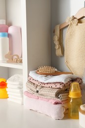 Photo of Baby clothes, toy and accessories on white rack