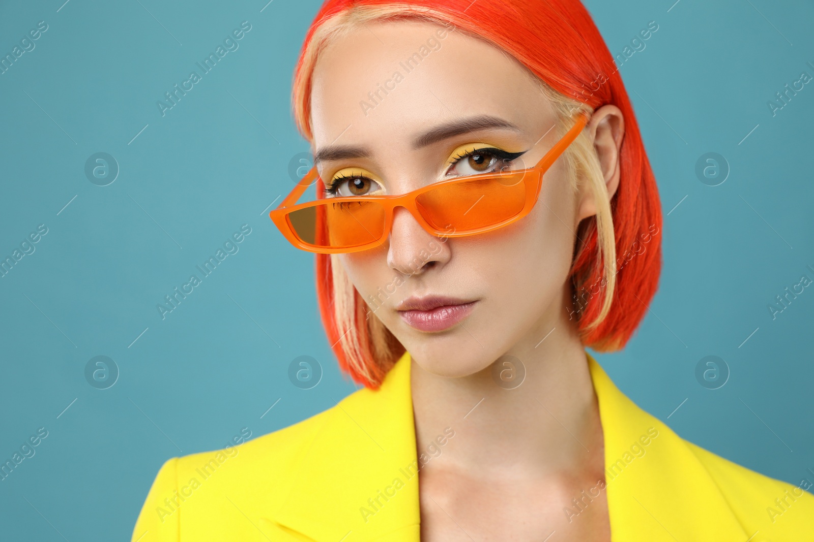 Photo of Beautiful young woman with bright dyed hair on turquoise background, closeup