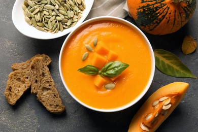 Photo of Flat lay composition with bowl of pumpkin soup on gray background