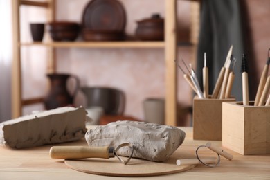 Photo of Clay and set of modeling tools on wooden table in workshop