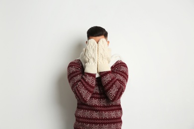 Photo of Man in Christmas sweater hiding his face on white background