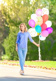 Photo of Young woman with colorful balloons in park on sunny day