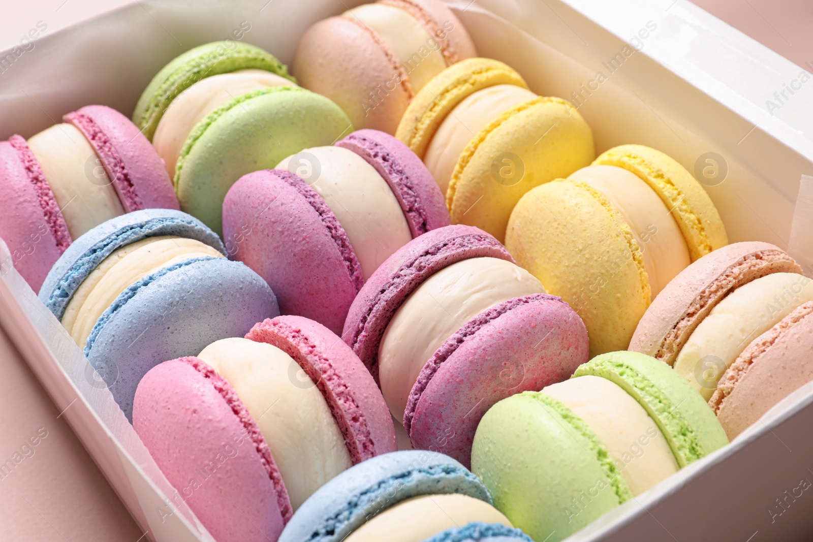 Photo of Many delicious colorful macarons in box, closeup