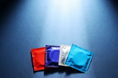 Photo of Packaged condoms on blue background, top view with space for text. Safe sex