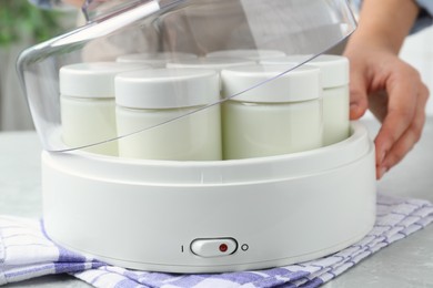 Photo of Woman making tasty yogurt at light grey marble table, closeup