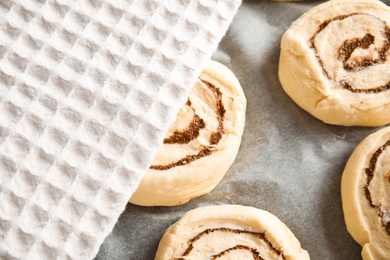 Photo of Raw cinnamon rolls and towel on parchment, closeup
