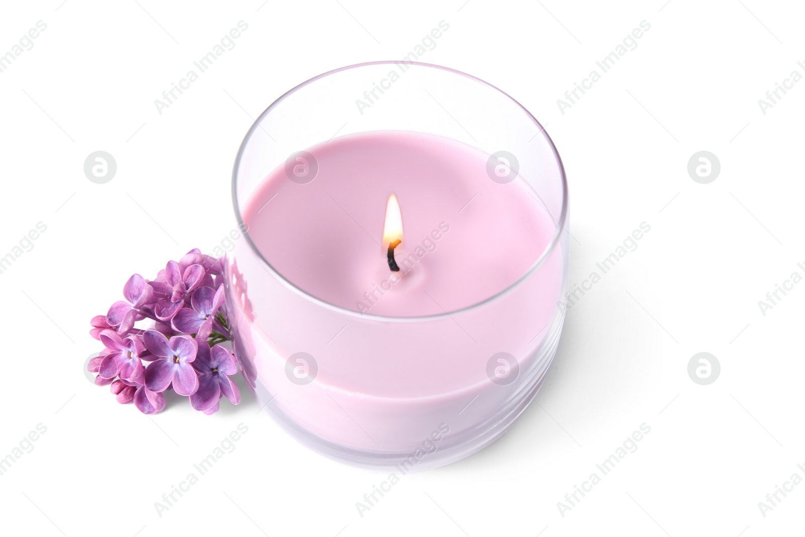 Photo of Pink wax candle in glass holder and lilac flowers isolated on white